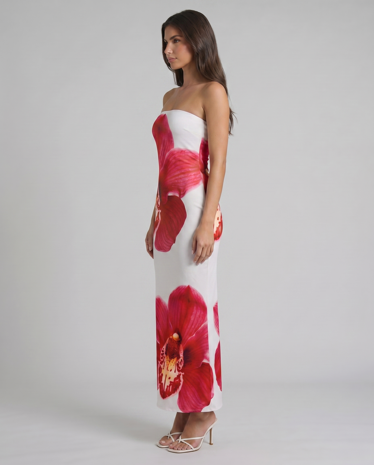 Side profile of strapless white maxi dress with red orchid floral print and straight hemline