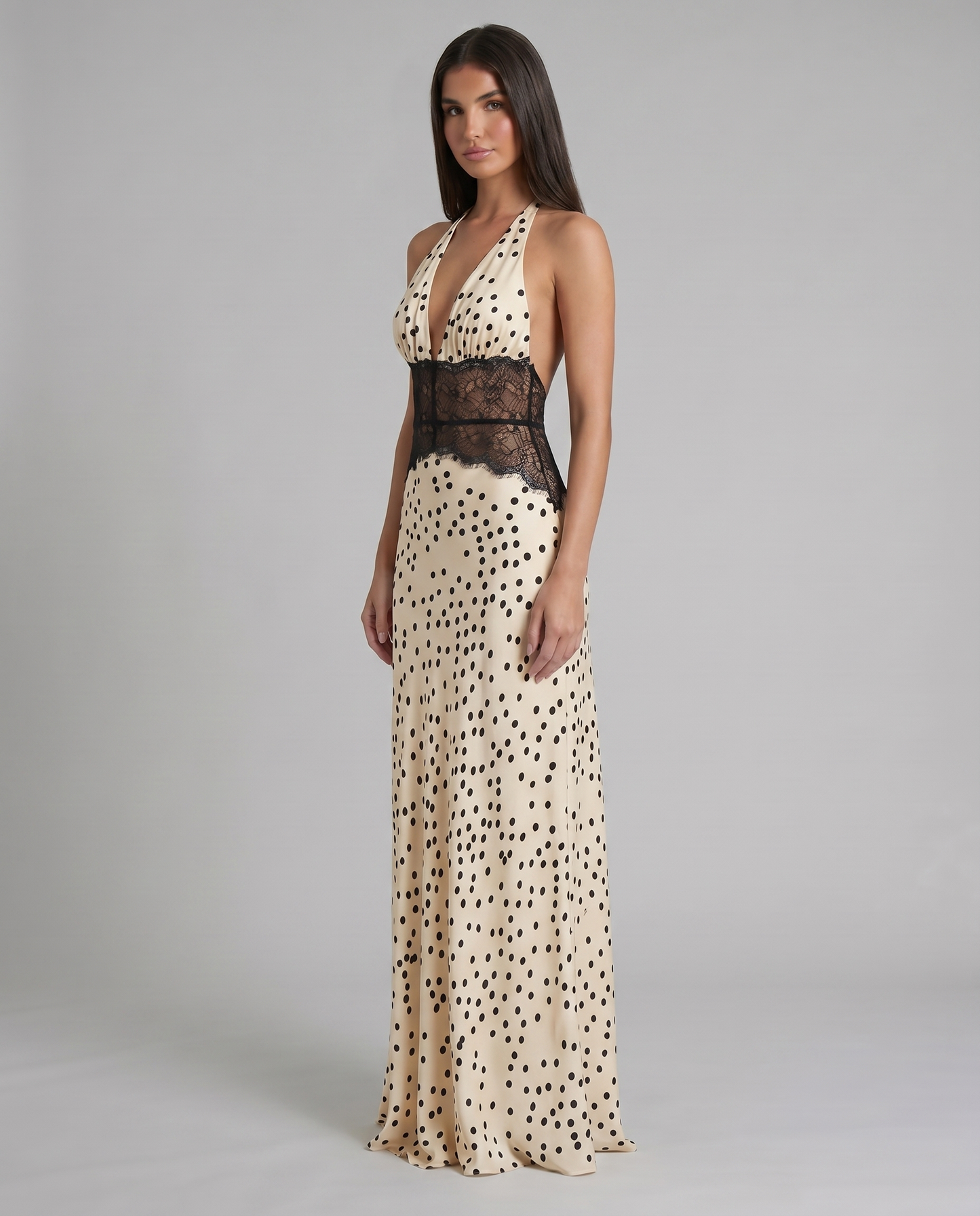 Angled front shot of black and white polka dot maxi dress highlighting lace waist and flowing hem