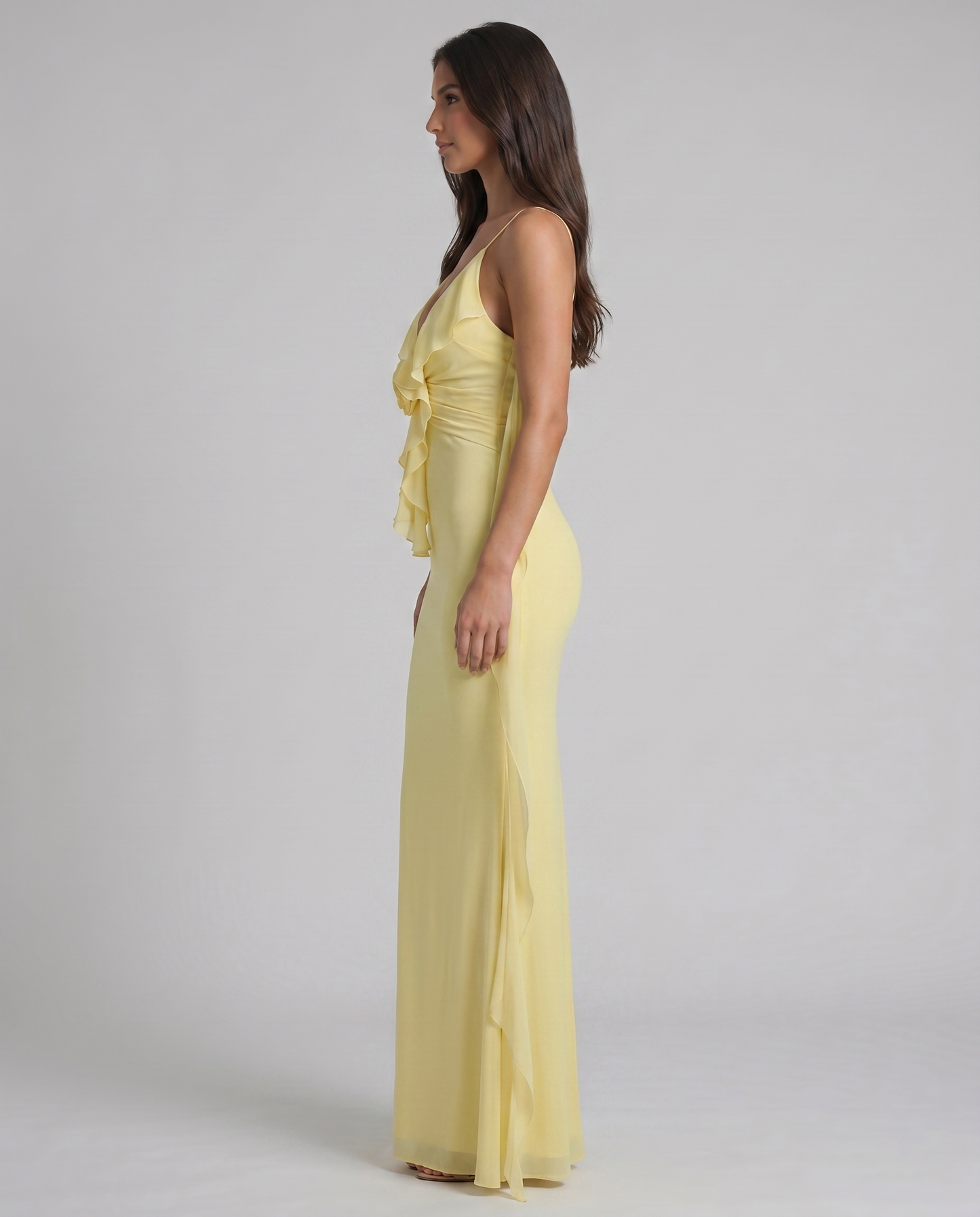 Side profile of yellow maxi dress with fitted silhouette, ruffle bodice and long sheer drape panel