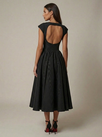 Back view black midi dress featuring a wide open back and full pleated skirt silhouette