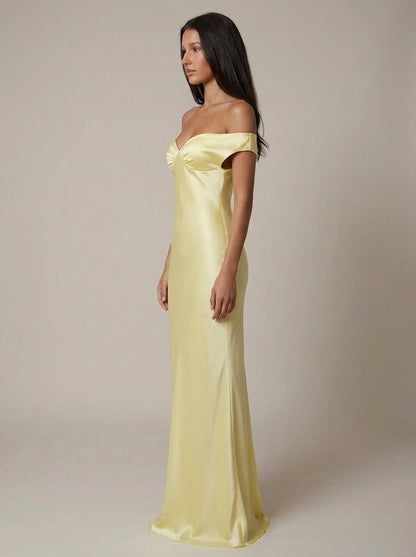 Side profile yellow satin maxi dress with off-shoulder sleeves and floor-length drape