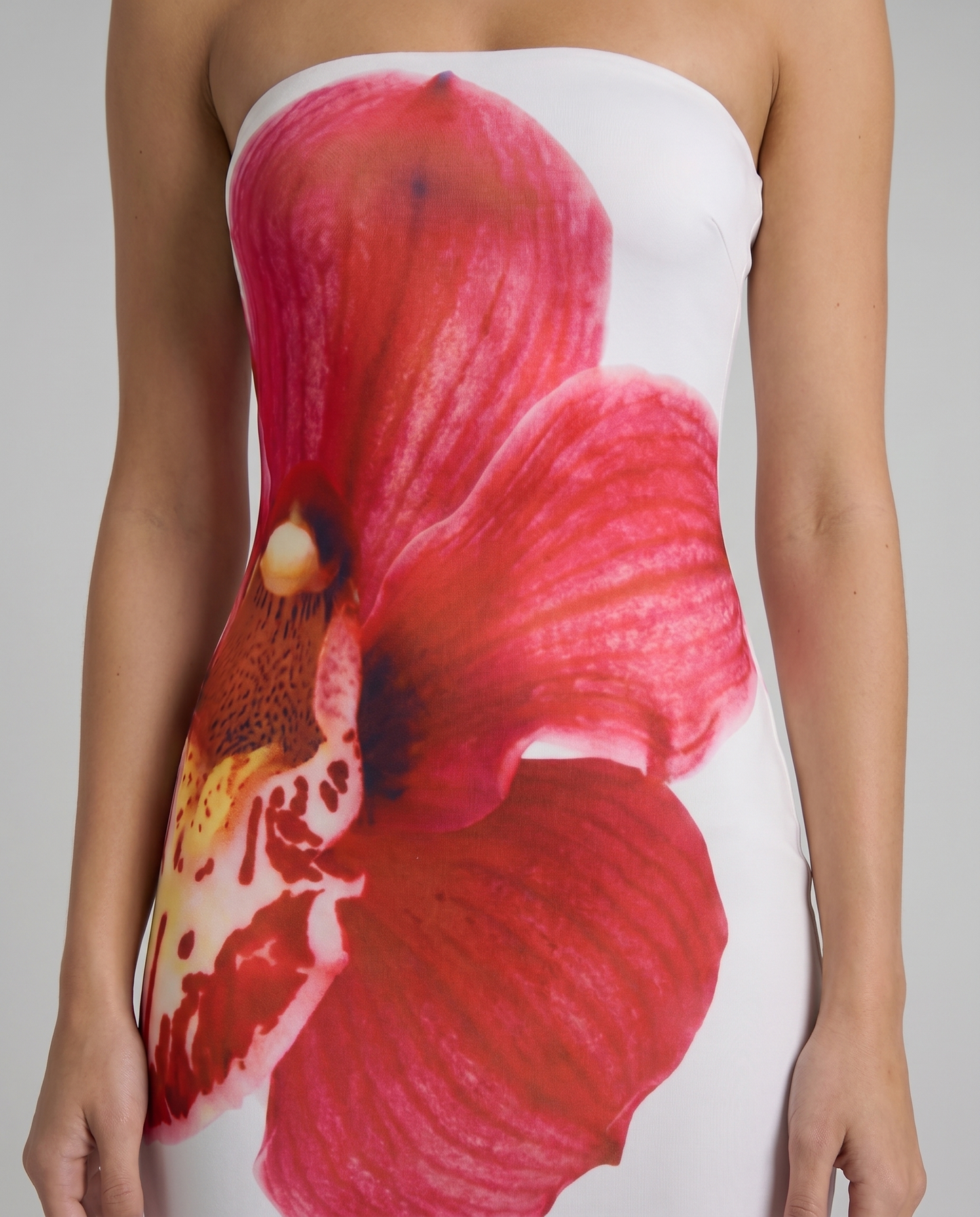 Close-up of strapless white maxi dress bodice with vibrant red orchid flower print detail