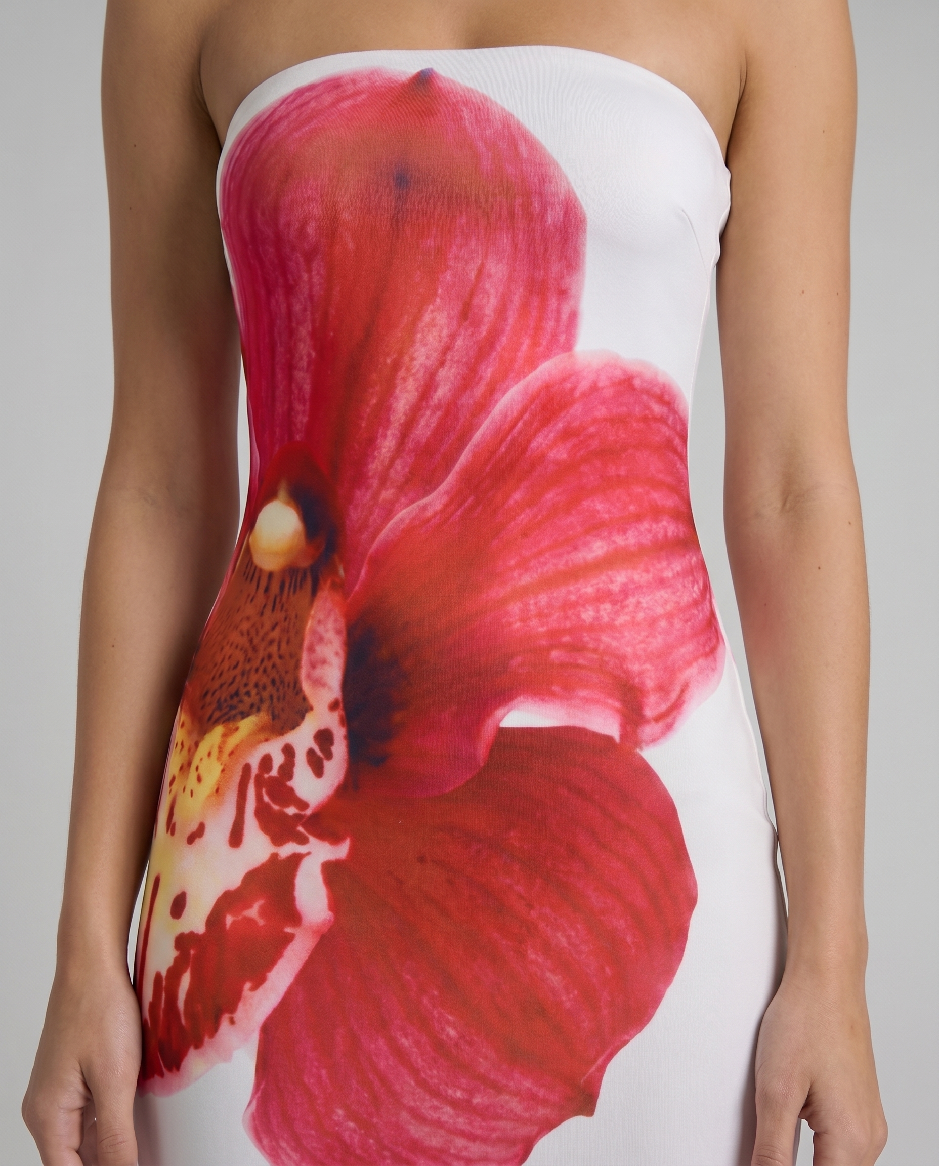 Close-up of strapless white maxi dress bodice with vibrant red orchid flower print detail