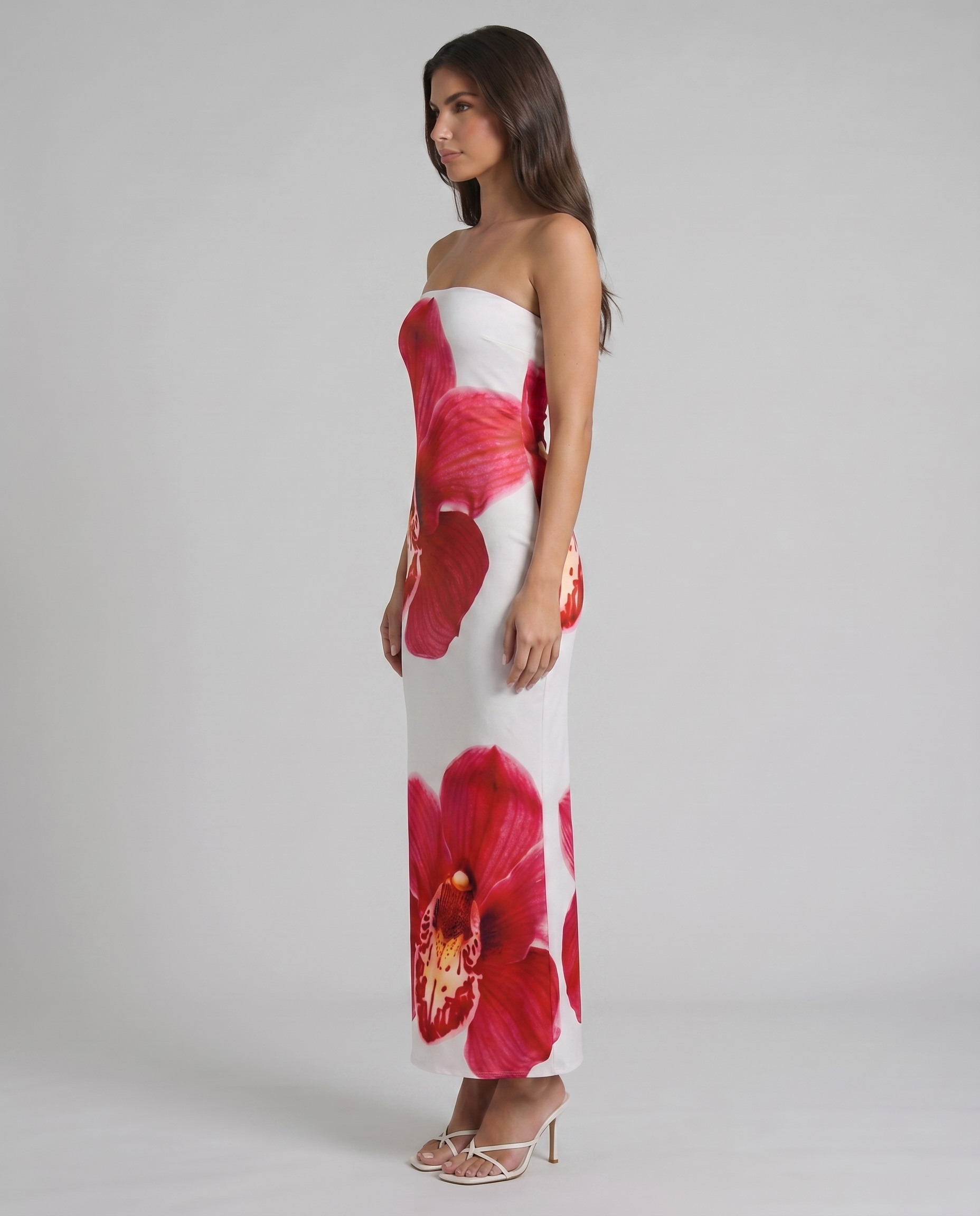 Side profile of strapless white maxi dress with red orchid floral print and straight hemline