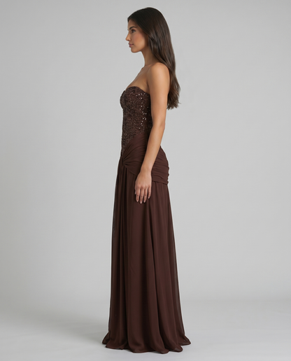 Side profile brown strapless maxi dress showing fitted beaded bodice and straight floor-length skirt