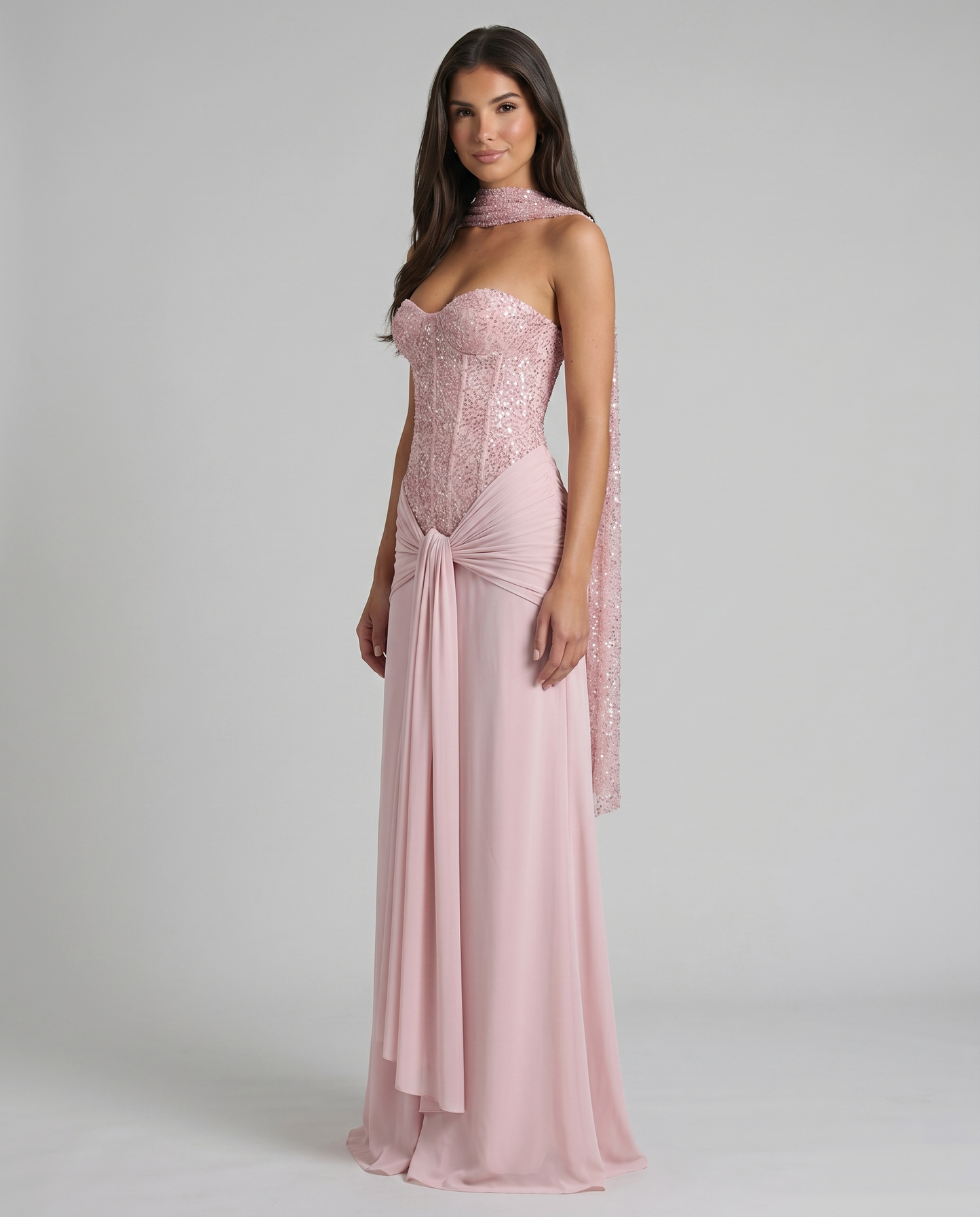 Angled side view of pink sequin corset maxi dress showing the waist knot drape and soft A-line skirt