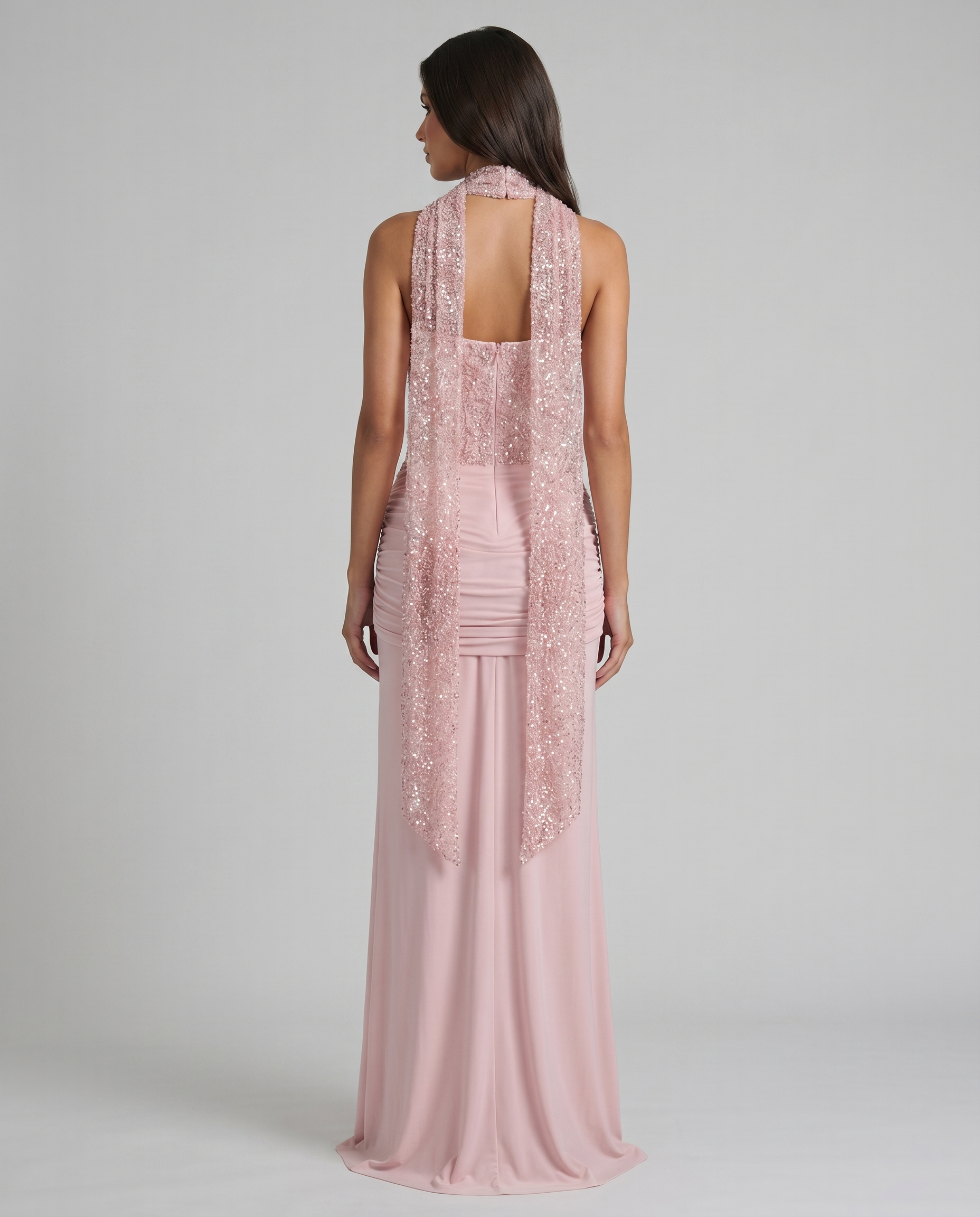 Back view of blush pink maxi dress with open back, sequin corset panel, and long scarf drape detail