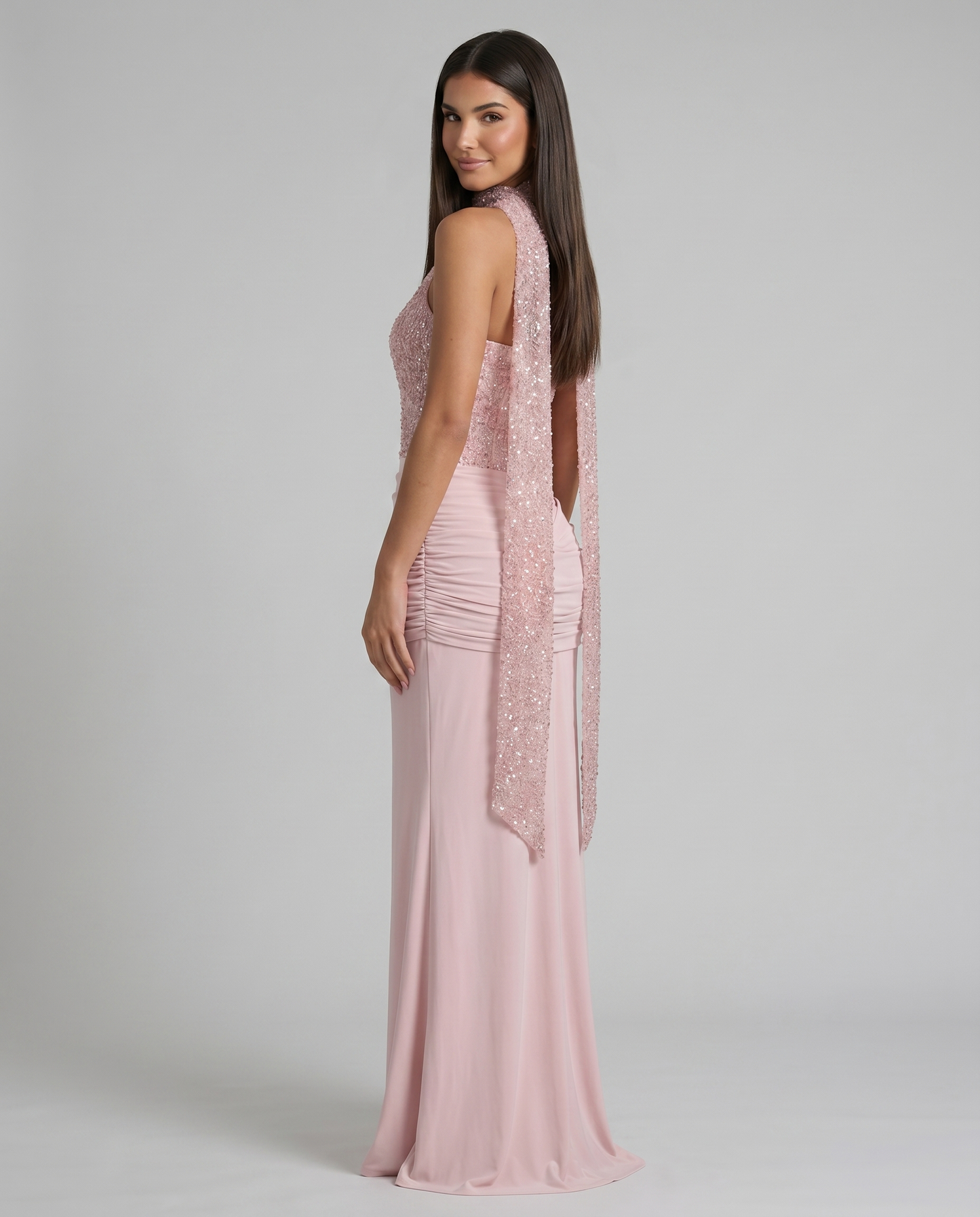 Over-the-shoulder side view of pink maxi dress highlighting the sequin scarf detail and ruched waist panel