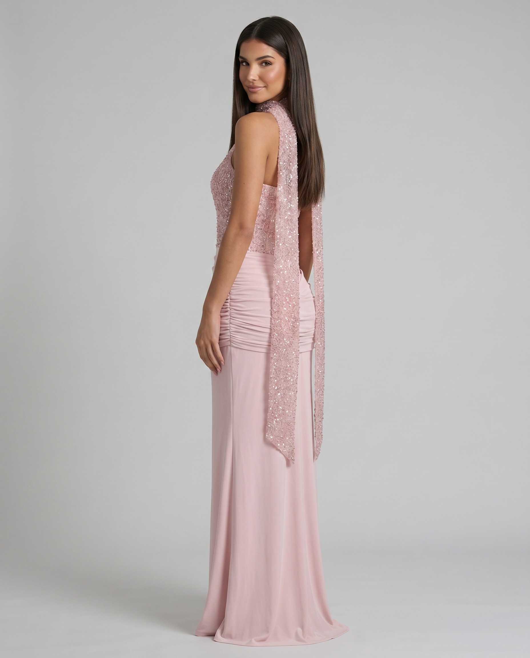 Over-the-shoulder side view of pink maxi dress highlighting the sequin scarf detail and ruched waist panel