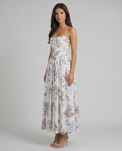 Angled view of purple floral midi dress with spaghetti straps, fitted bodice, and gathered skirt