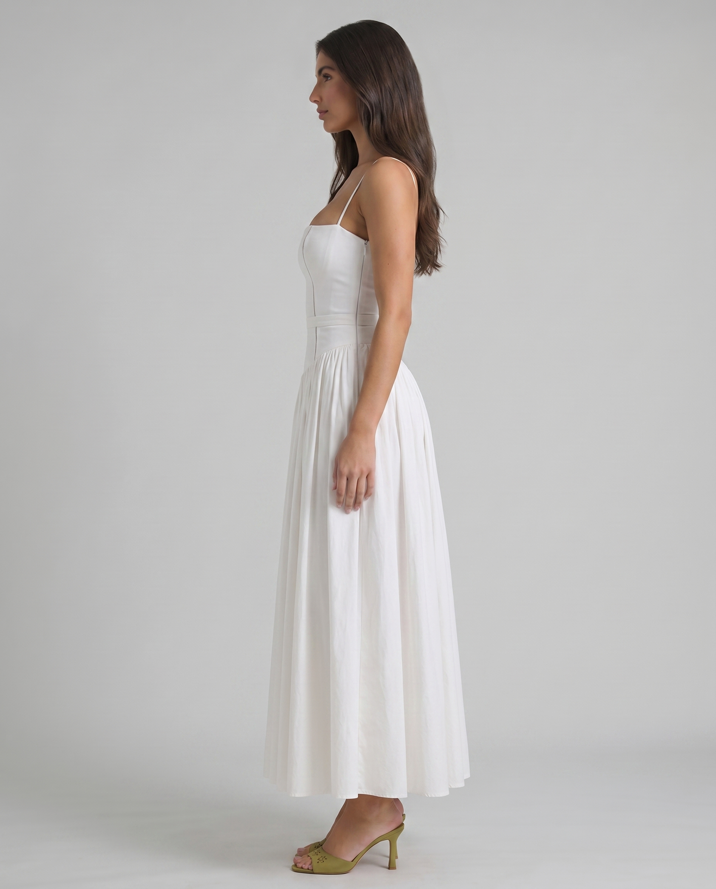 Side profile of white midi dress with structured bodice, slim waist band and mid-length skirt