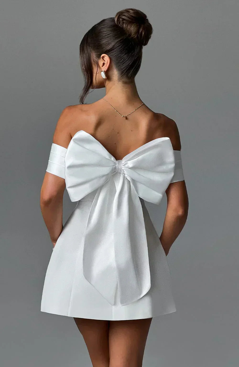 Back view white off-shoulder mini dress with oversized bow detail across the shoulders