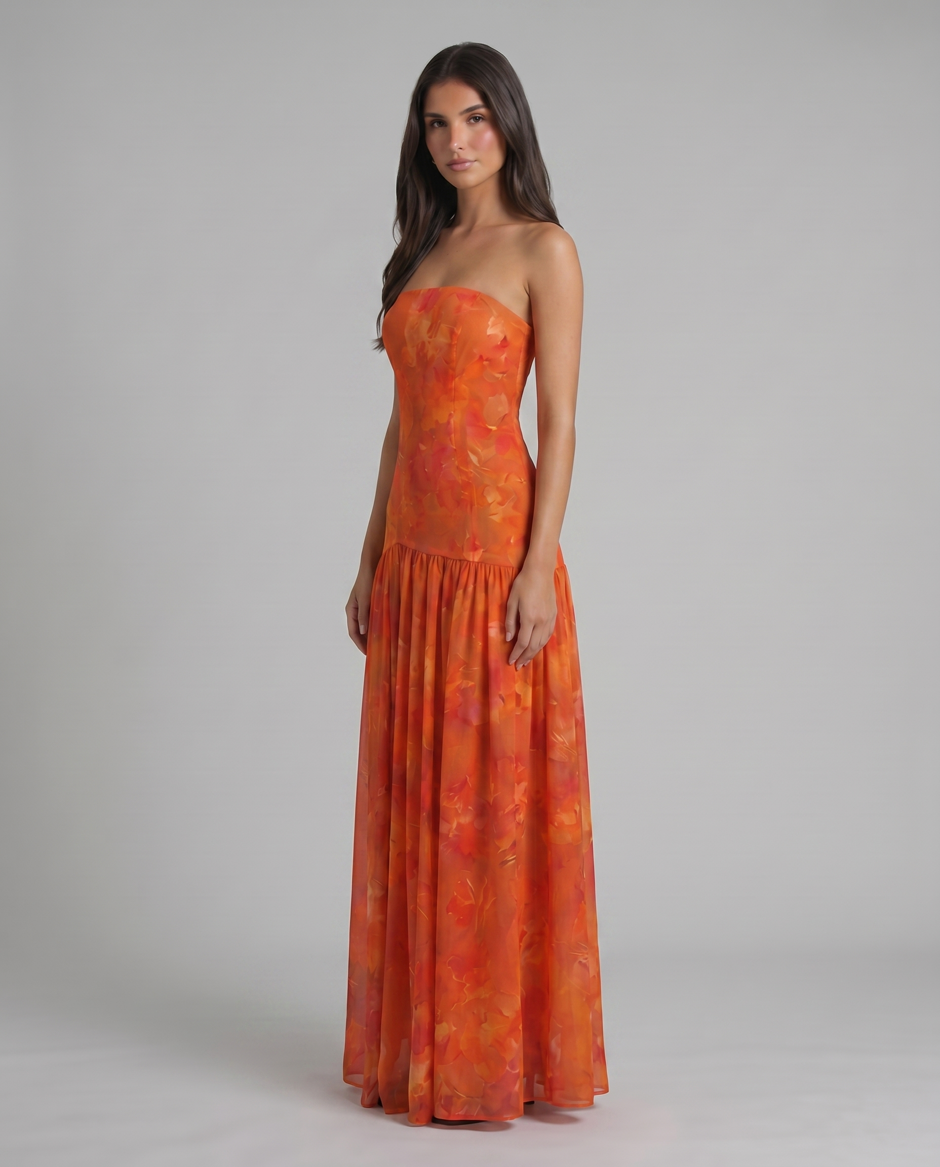 Three-quarter view of red strapless maxi dress with watercolor floral print and drop-waist seam