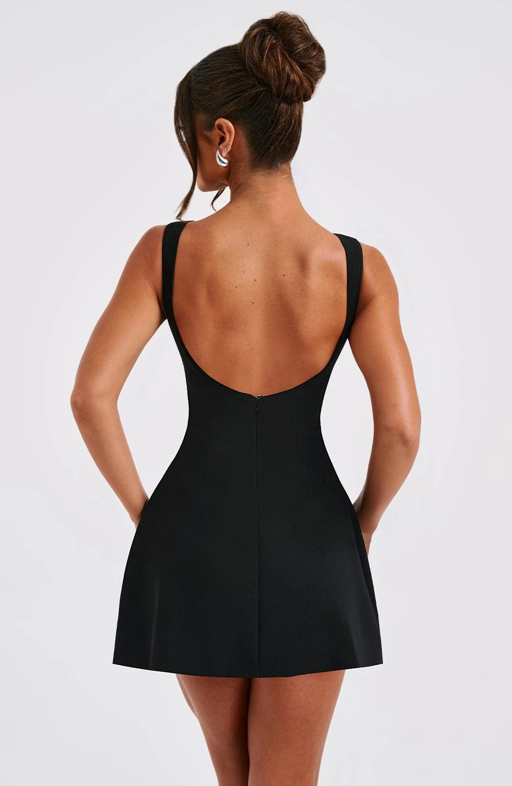 Back view of black sleeveless mini dress with scoop back, hidden zipper and flared skirt