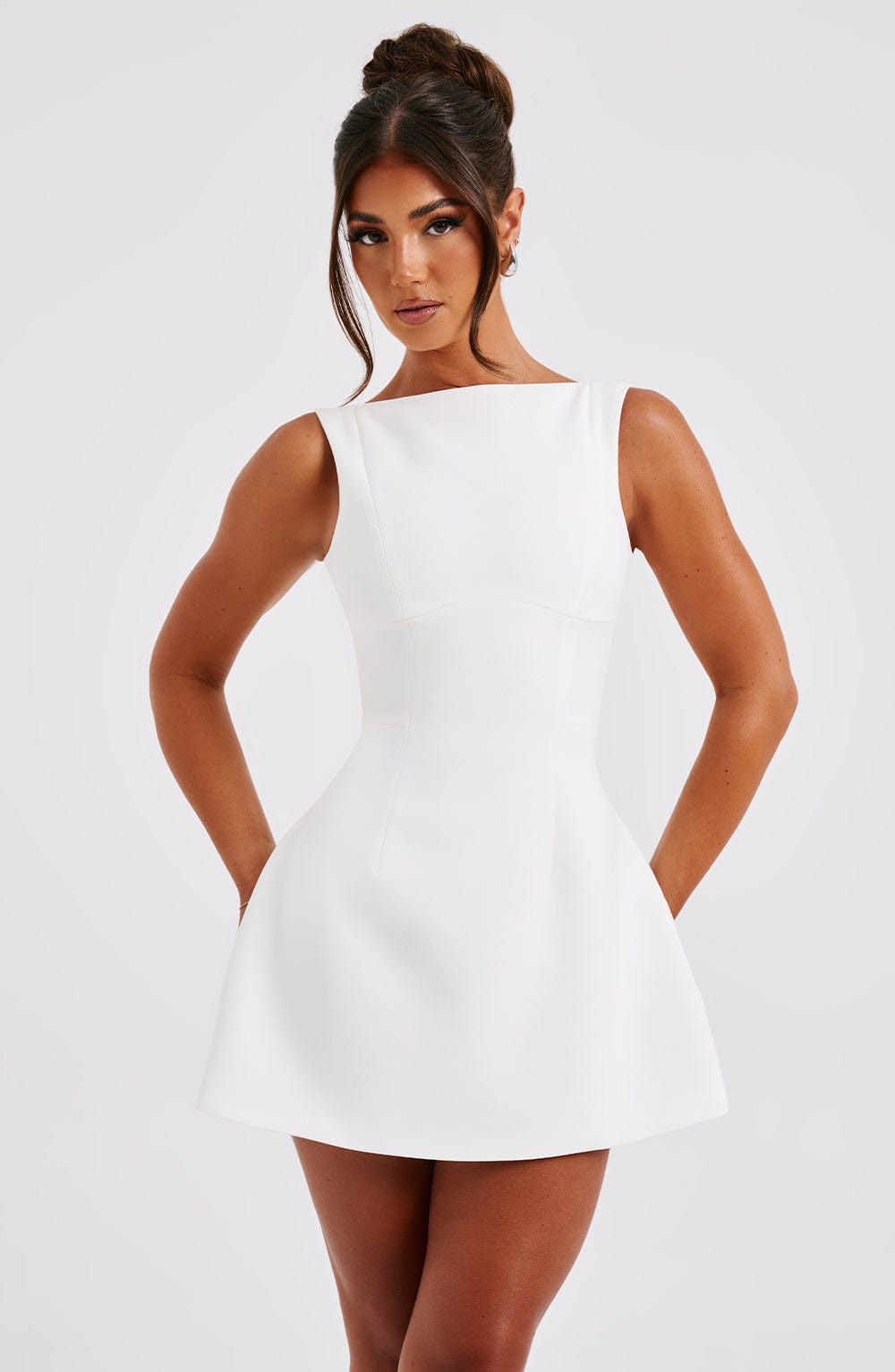 White structured mini dress with fitted waist seams and wide straps, studio front angle