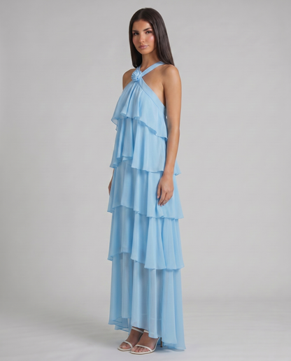 Three-quarter view of blue ruffle maxi dress with halter rosette flower and layered hem