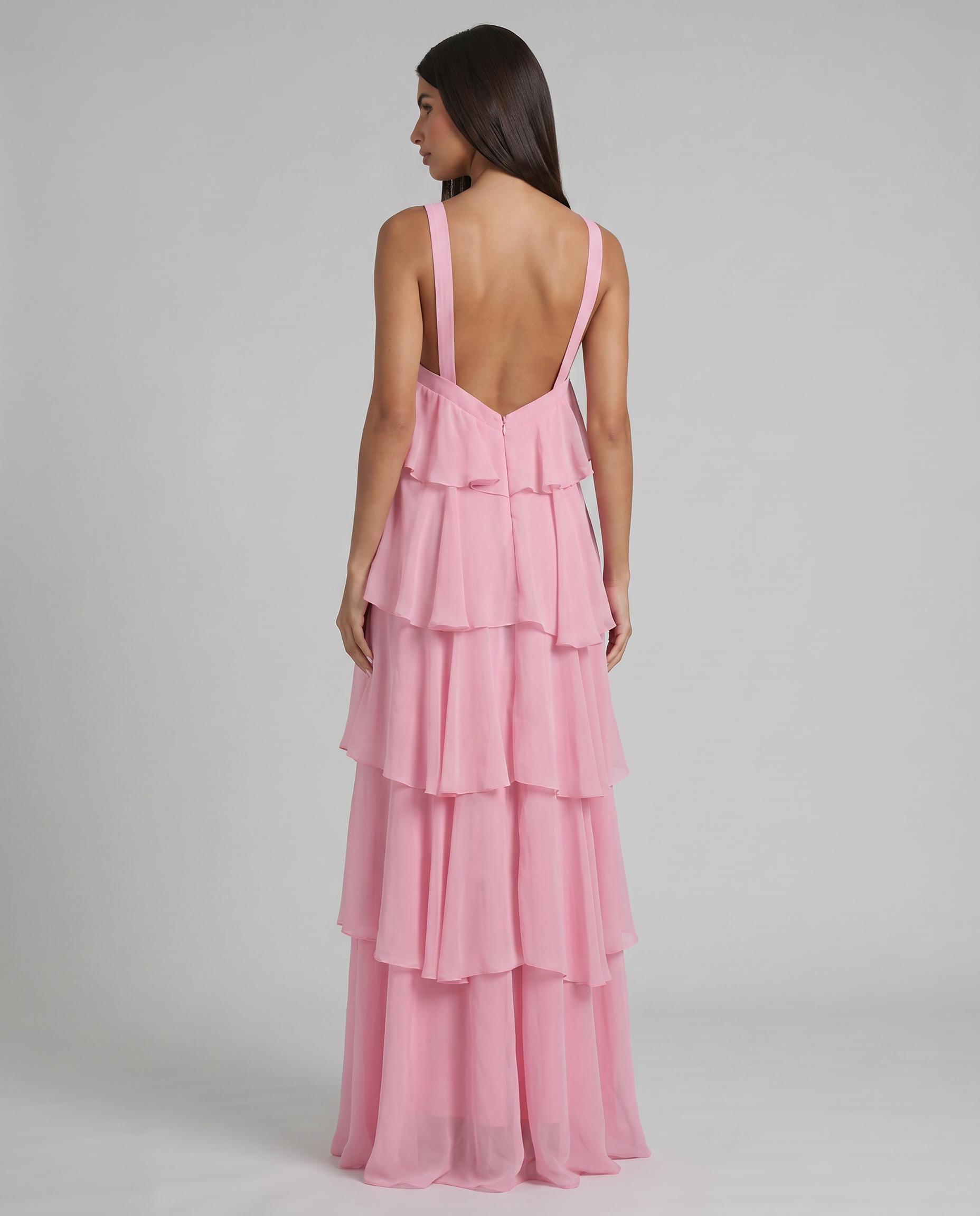 Back view of pink ruffle maxi dress showing low V-back straps, center zipper, and tiered skirt