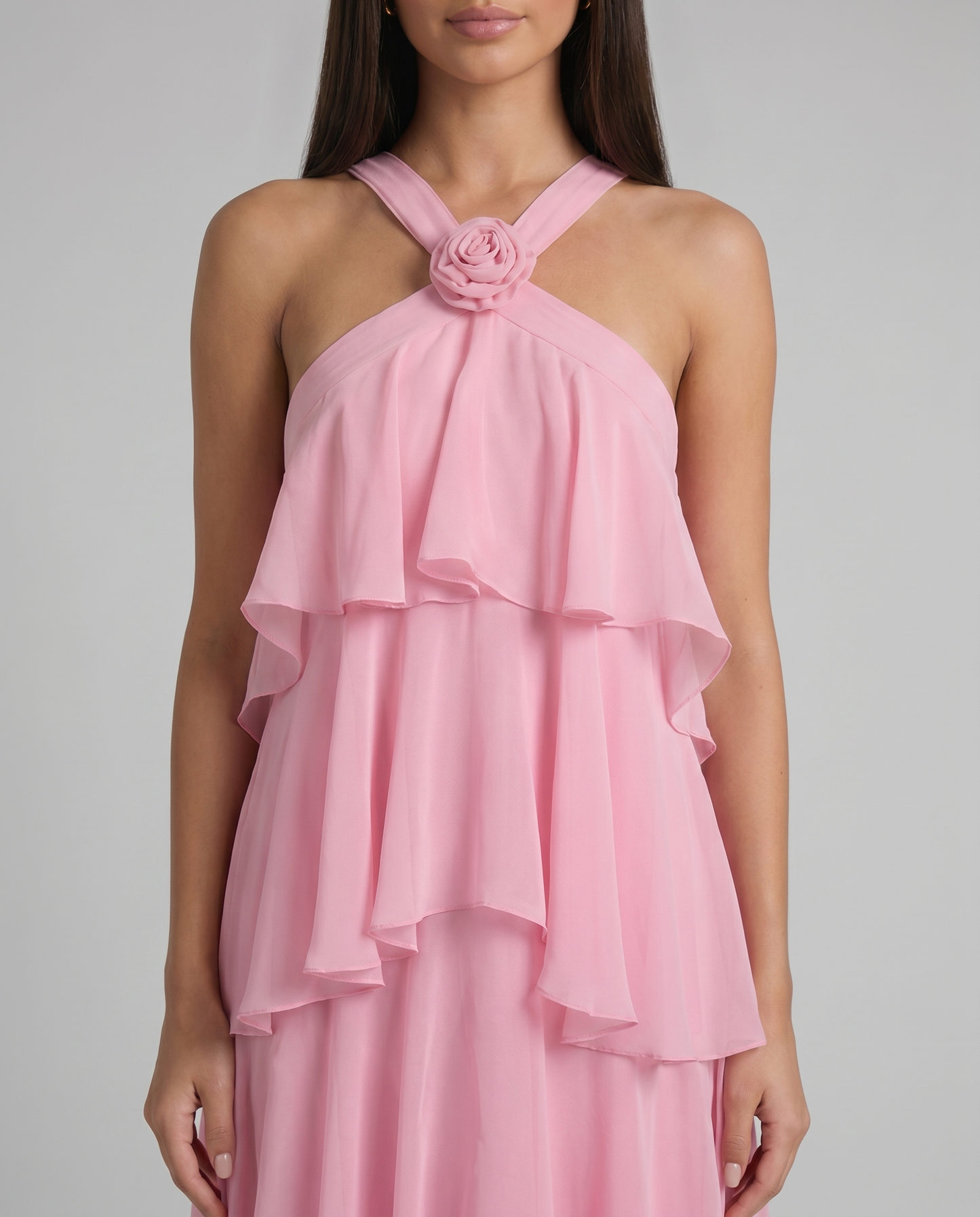 Detail of pink maxi dress crisscross halter straps with fabric rosette at neckline and airy ruffle overlay
