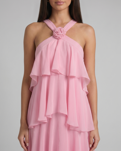 Detail of pink maxi dress crisscross halter straps with fabric rosette at neckline and airy ruffle overlay