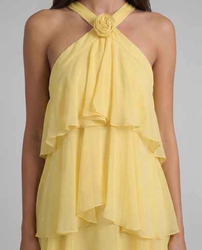 Close-up of yellow maxi dress halter with floral rosette detail and soft ruffle overlay at bust