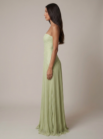 Side profile of green maxi dress showing straight strapless neckline and flowing pleated hem