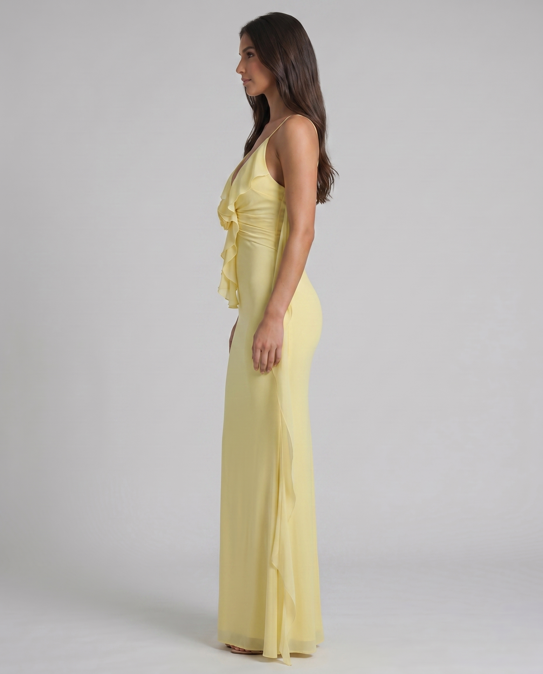 Side profile of yellow maxi dress with fitted silhouette, ruffle bodice and long sheer drape panel