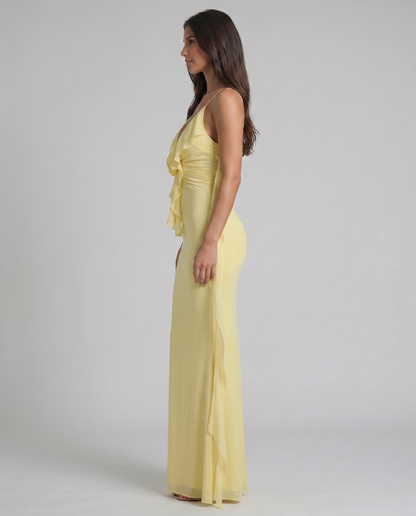 Side profile of yellow maxi dress with fitted silhouette, ruffle bodice and long sheer drape panel