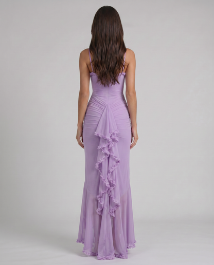 Back view of purple maxi dress with fitted bodice, ruched skirt, and ruffle-edged back drape panel