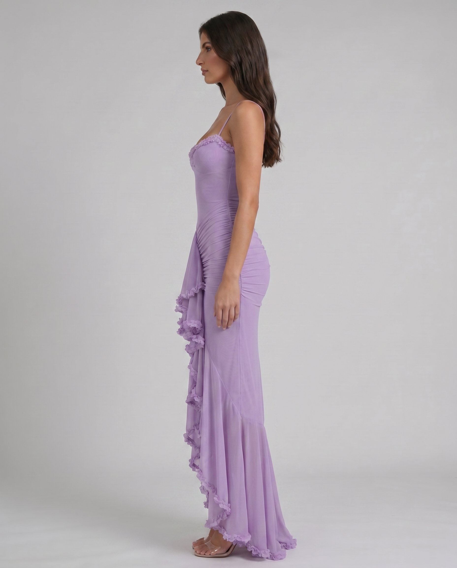 Side profile of purple maxi dress with spaghetti straps, ruched silhouette, and ruffle high-low hem