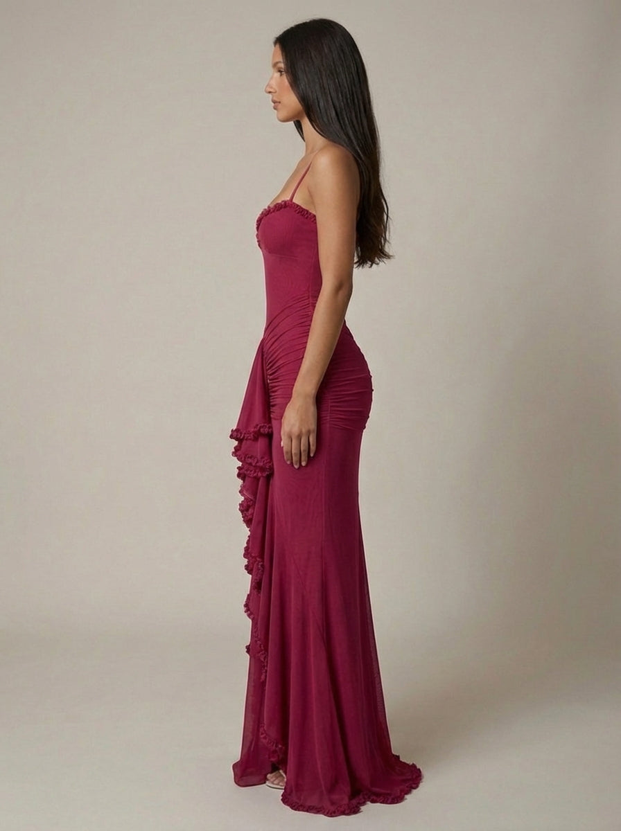 Side view of deep red maxi dress with bodycon fit, ruched hip panels, and floor-length hem