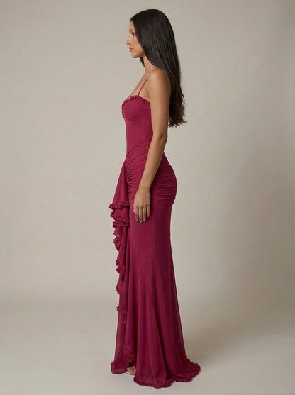 Side view of deep red maxi dress with bodycon fit, ruched hip panels, and floor-length hem