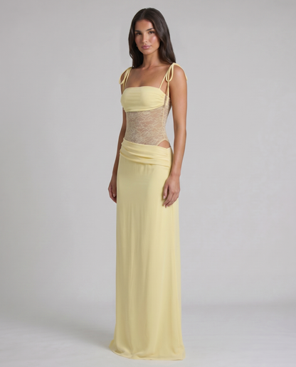 Hem detail of soft yellow maxi dress with flowing fabric drape and slight pooling at the floor