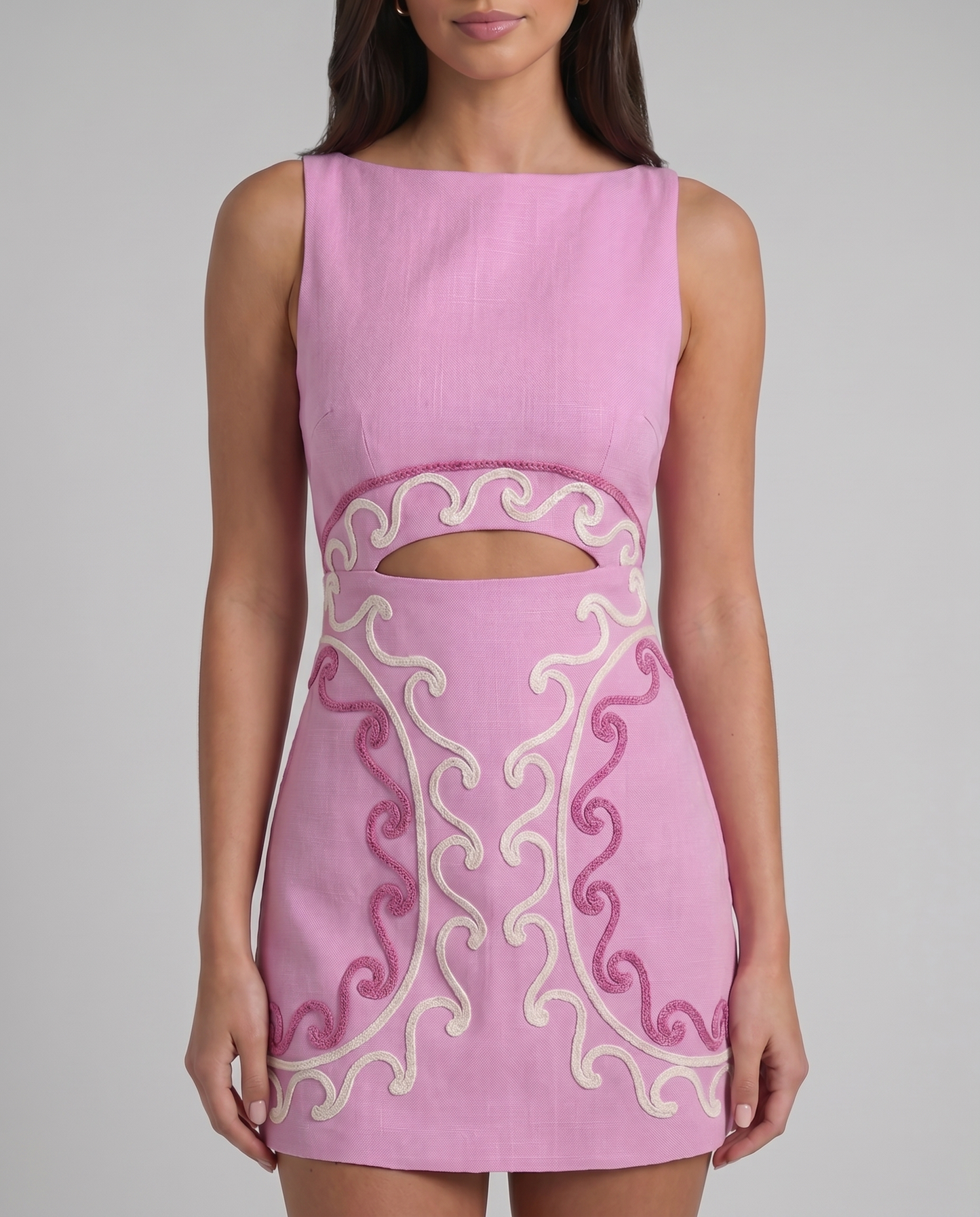 Close-up of pink mini dress bodice with boat neckline, curved waist cutout and embroidered trim