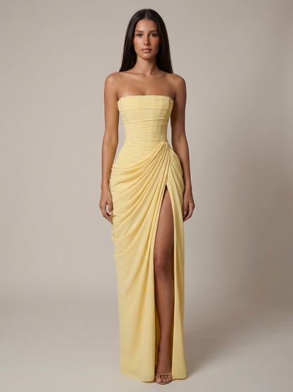 Front view of yellow strapless maxi dress with ruched bodice, draped skirt and high slit