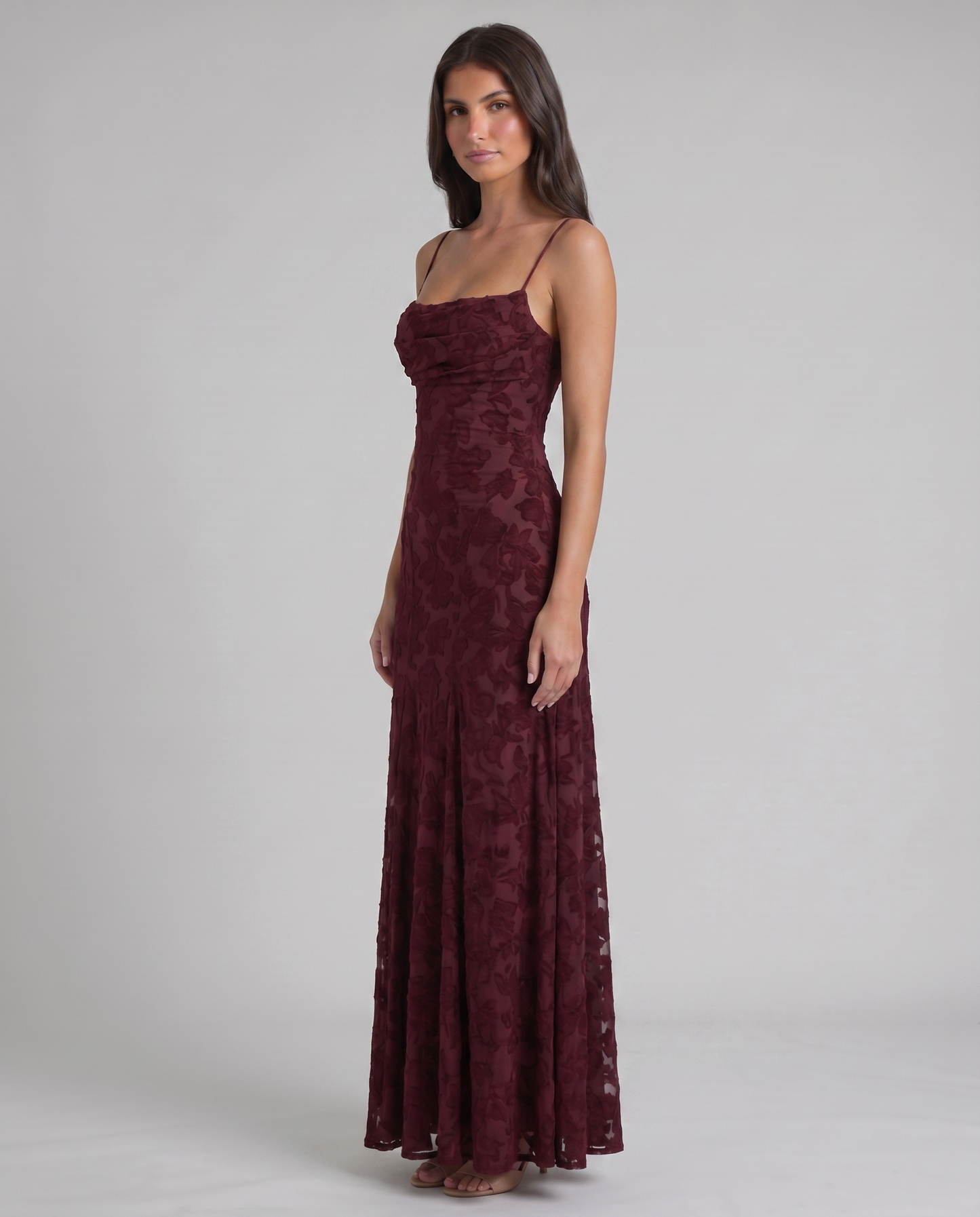 Angled front view burgundy maxi dress featuring fitted bodice and floral burnout mesh overlay