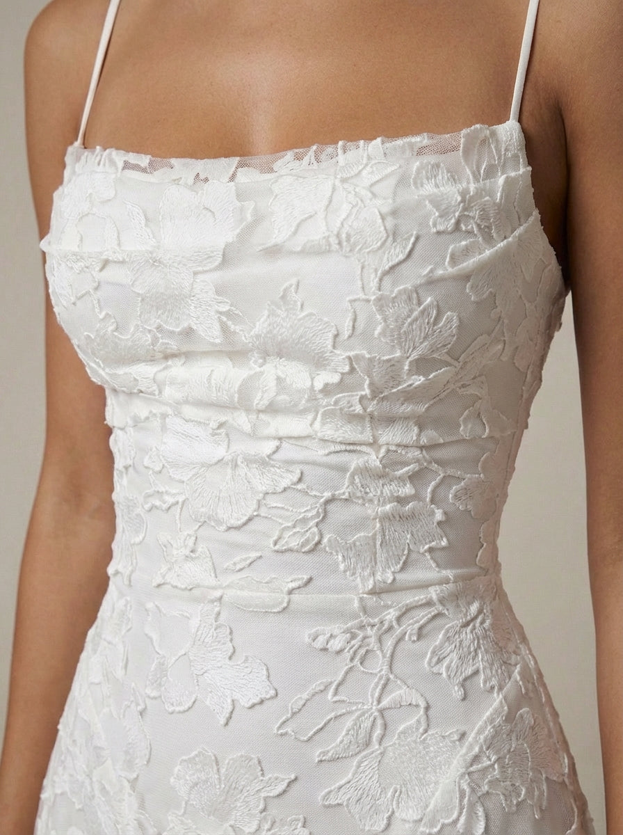 Close-up of white maxi dress bodice with straight neckline, spaghetti straps, and raised floral lace