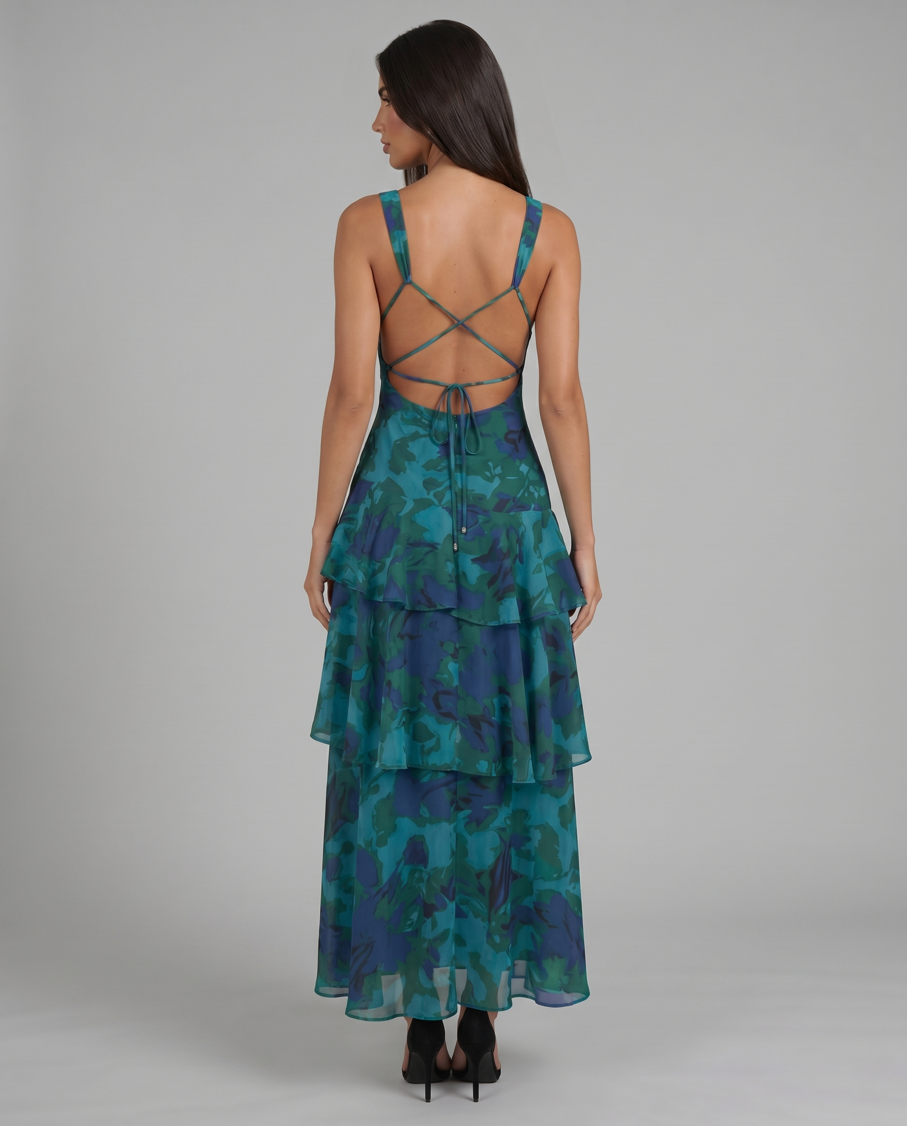 Back view of blue maxi dress with open back, crisscross straps, adjustable tie, and tiered hem