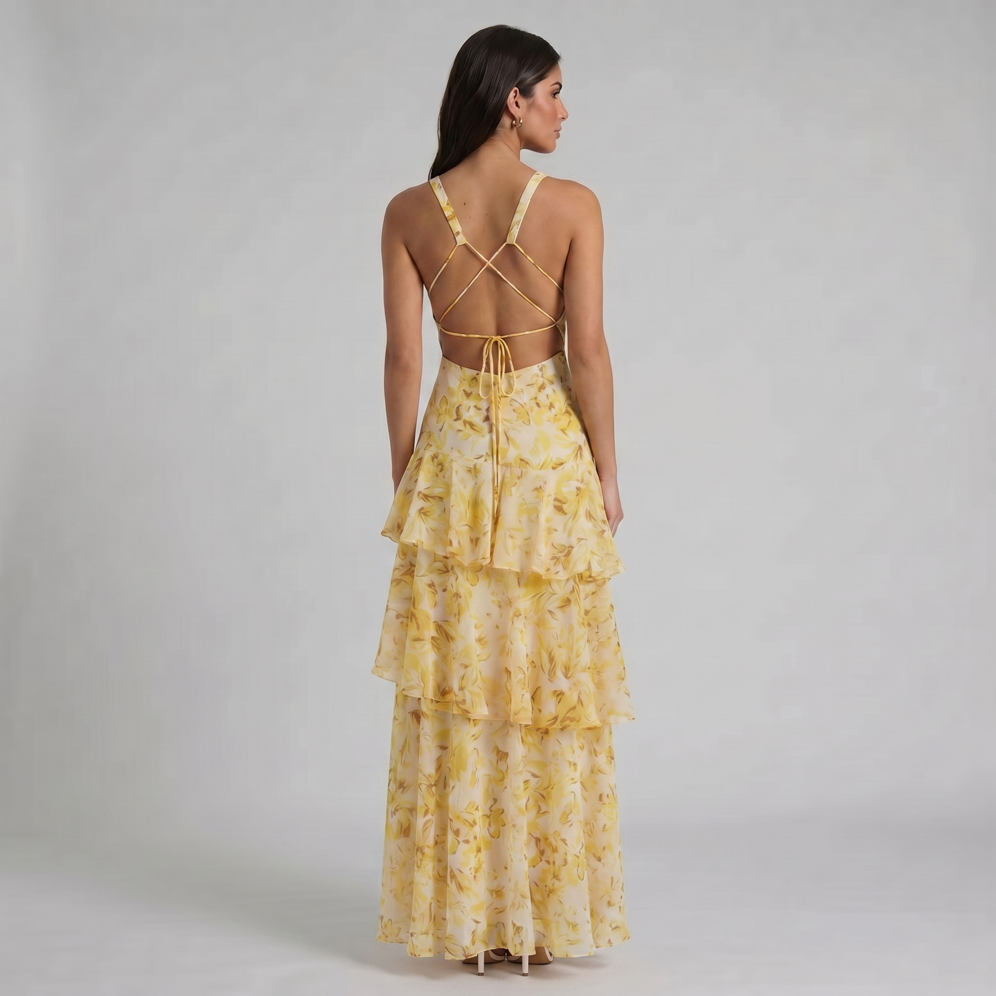 Back view of yellow floral maxi dress with open back, crisscross straps, and tie detail