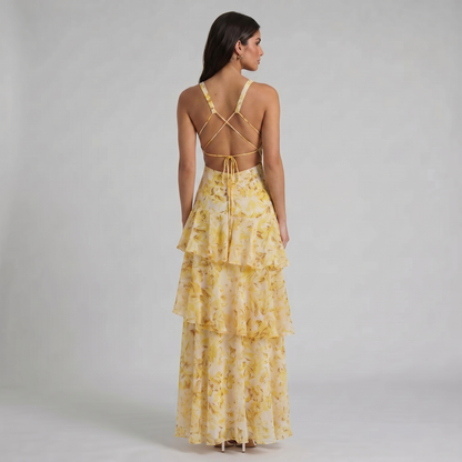Back view of yellow floral maxi dress with open back, crisscross straps, and tie detail
