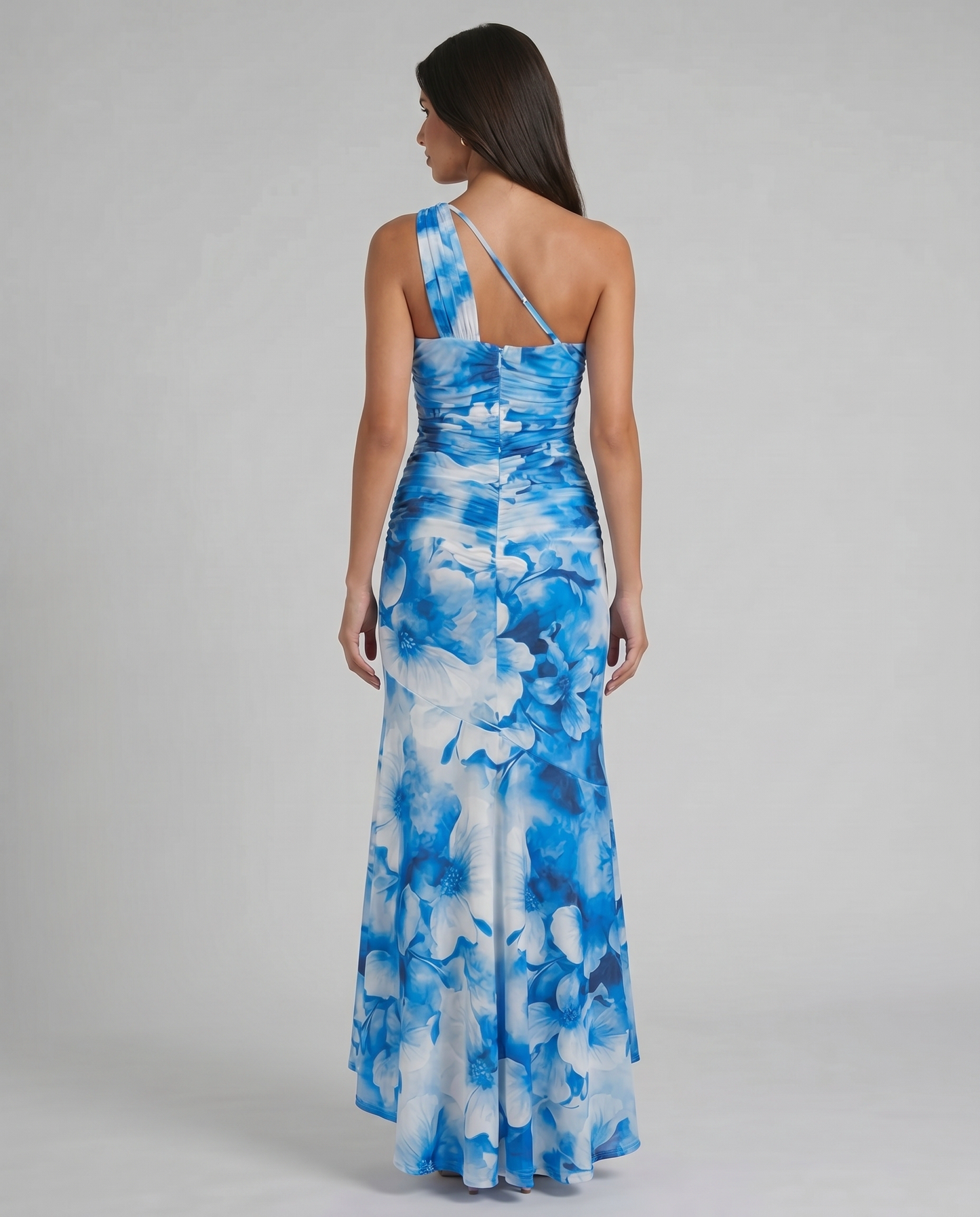 Back view of blue and white floral maxi dress with one-shoulder strap, slim back strap, and ruched waist