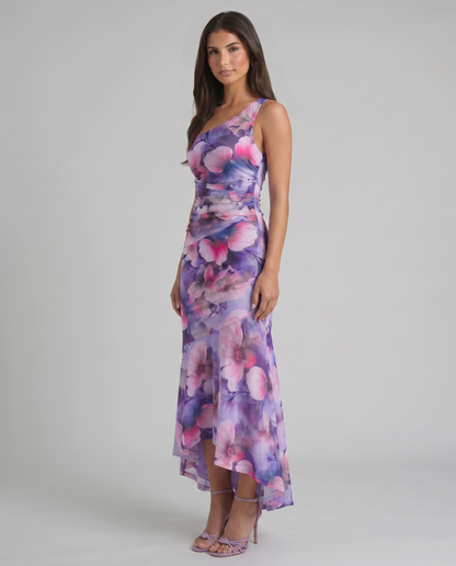 Purple floral maxi dress in angled view showing one-shoulder neckline, fitted ruching, flowy skirt