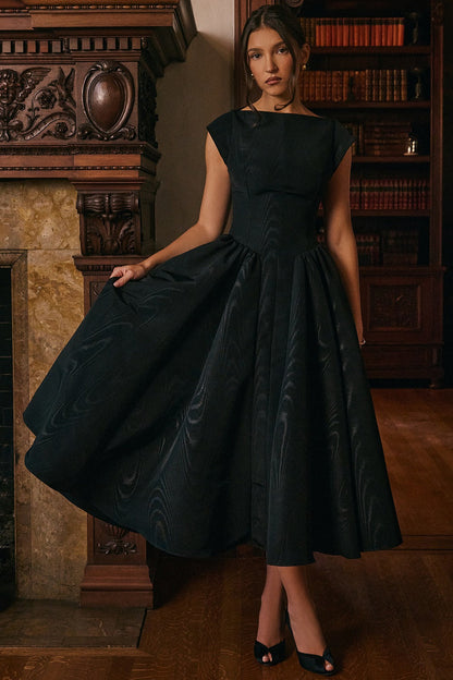 Black jacquard midi dress shown with flared skirt spread out, cap sleeves and fitted waist, indoor scene