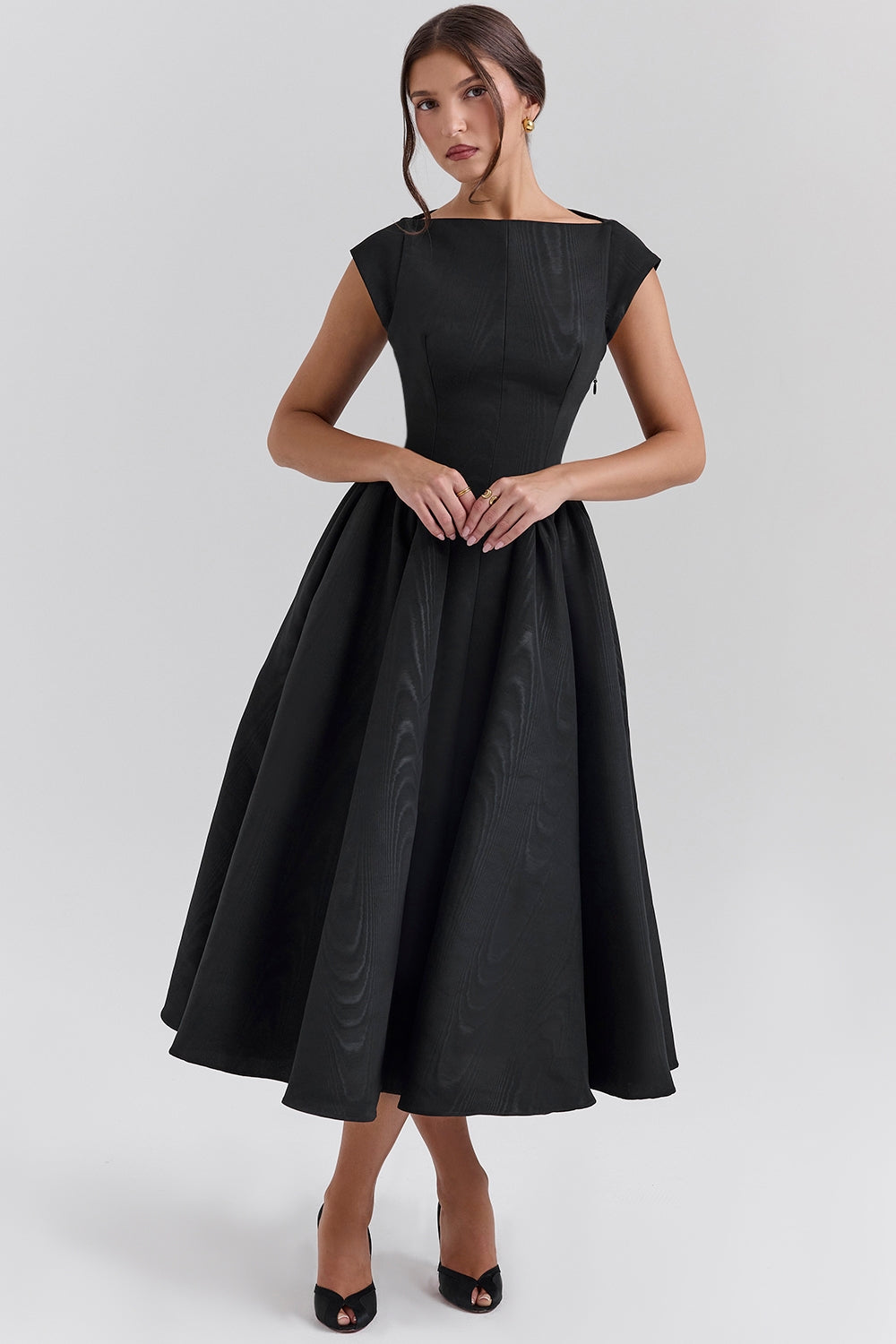Three-quarter view of black midi dress with structured bodice and voluminous skirt, calf length hem