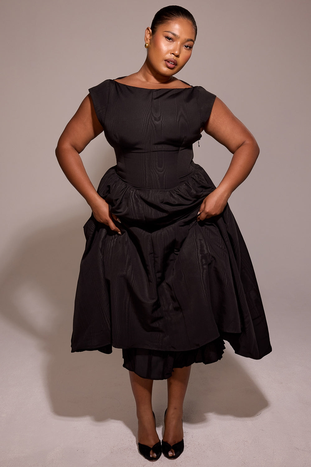 Black midi dress front view with draped full skirt, bateau neck and cap sleeves, studio lighting