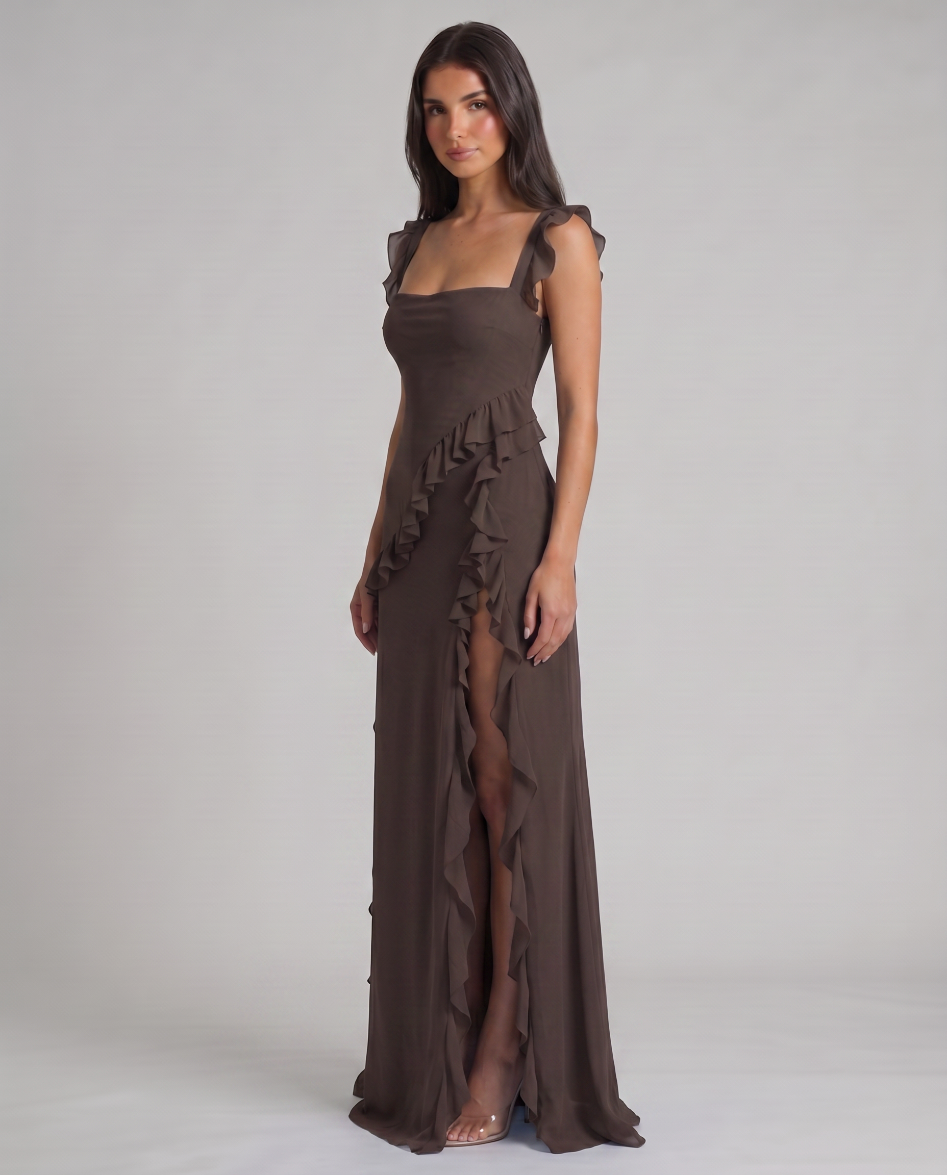 Angled view of black maxi dress featuring fitted bodice, flutter straps, ruffle cascade and thigh slit