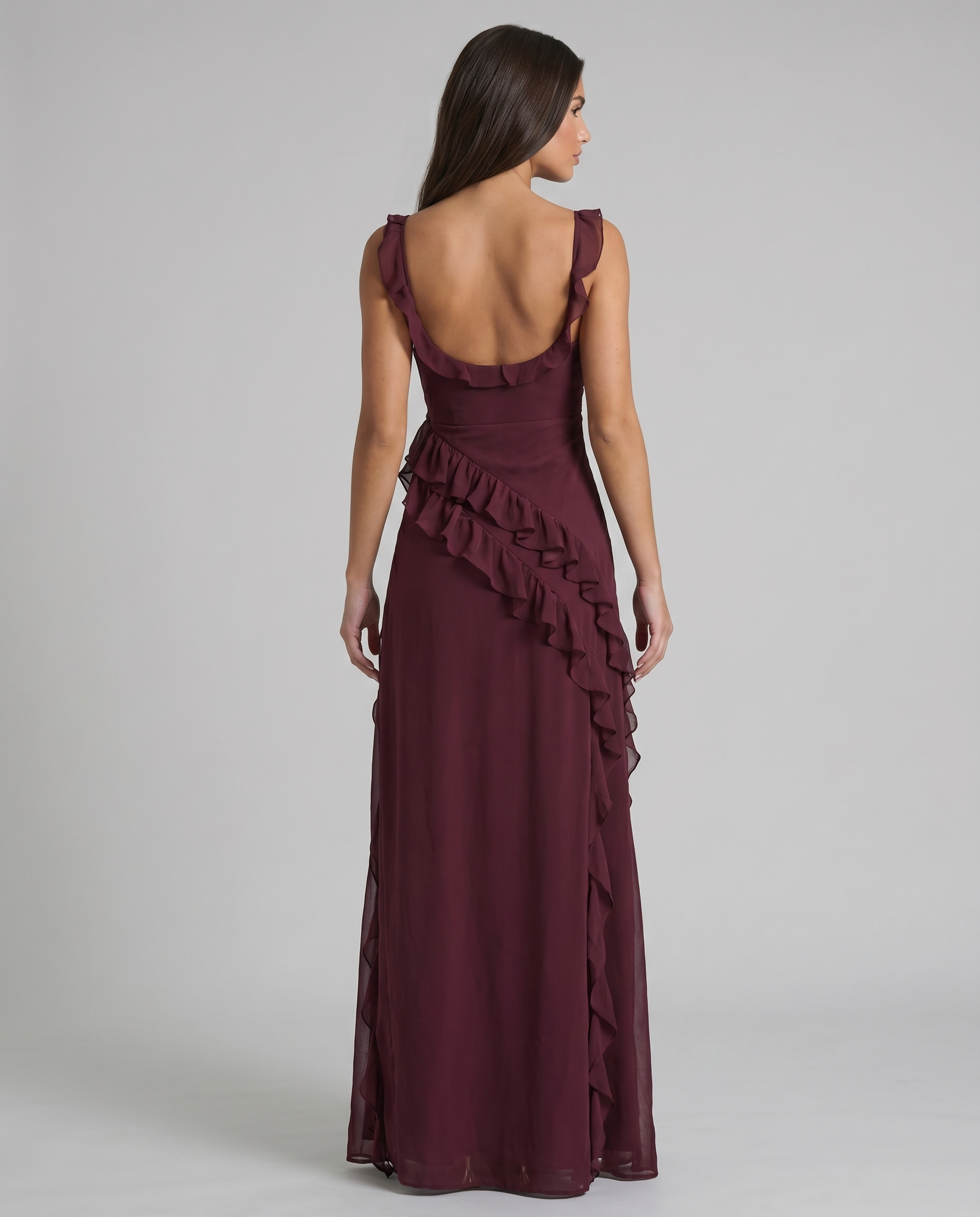 Back view of plum purple maxi dress with low scoop back, ruffle straps, and flowing skirt
