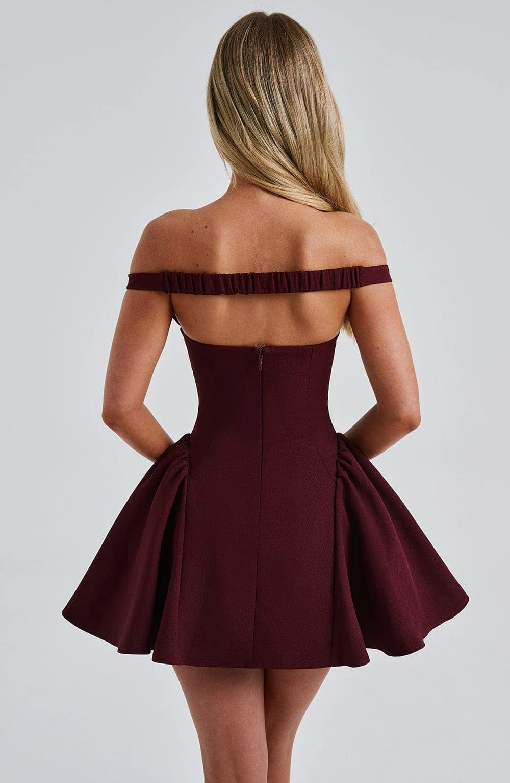 Back view of burgundy off shoulder mini dress showing straight neckline band, fitted waist and zipper