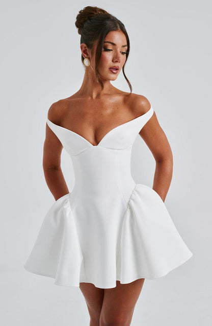 Three-quarter front view of white off-shoulder mini dress showing structured bodice and flounce skirt