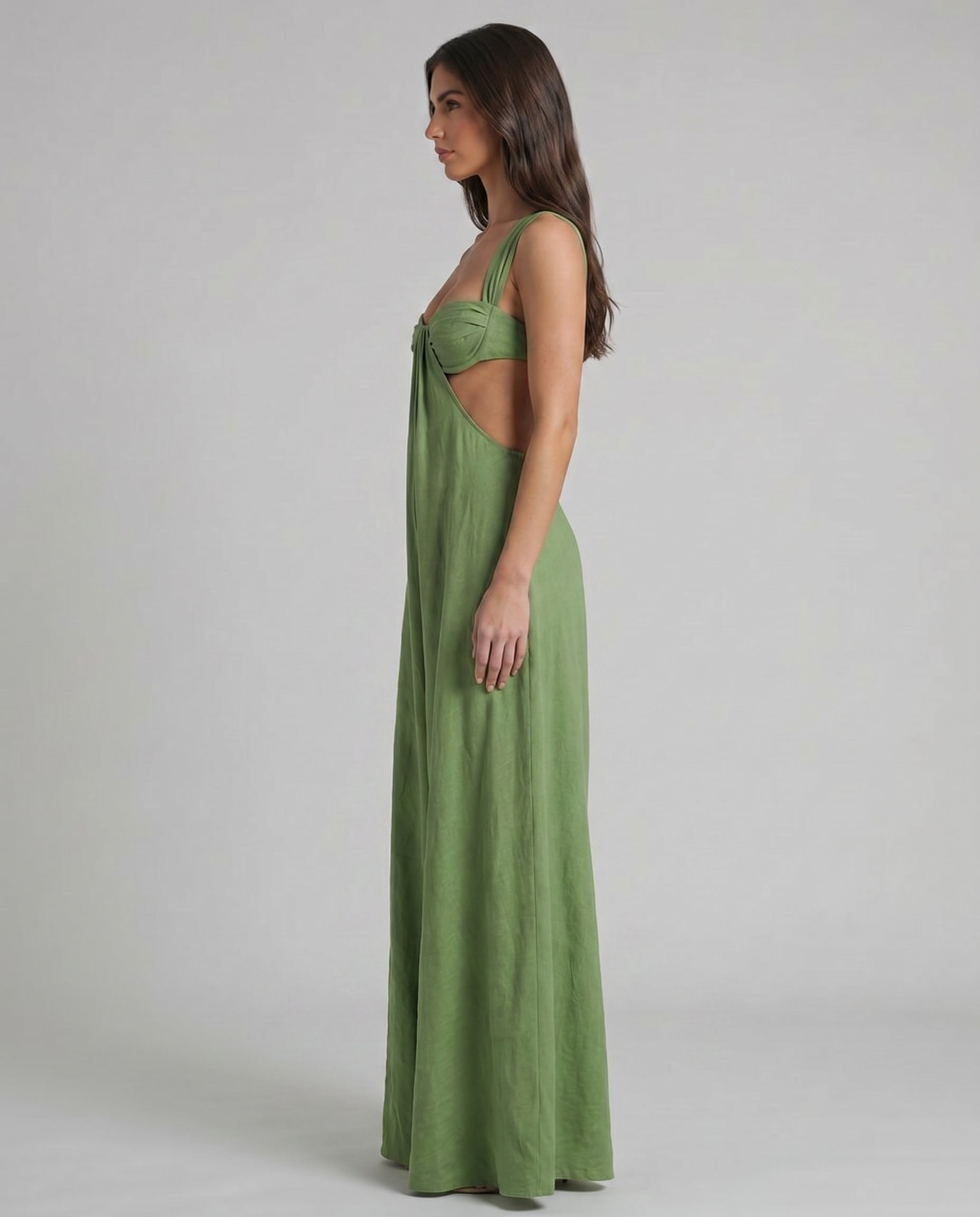 Side profile of green maxi dress showing cutout waist, bustier top, and long draped skirt