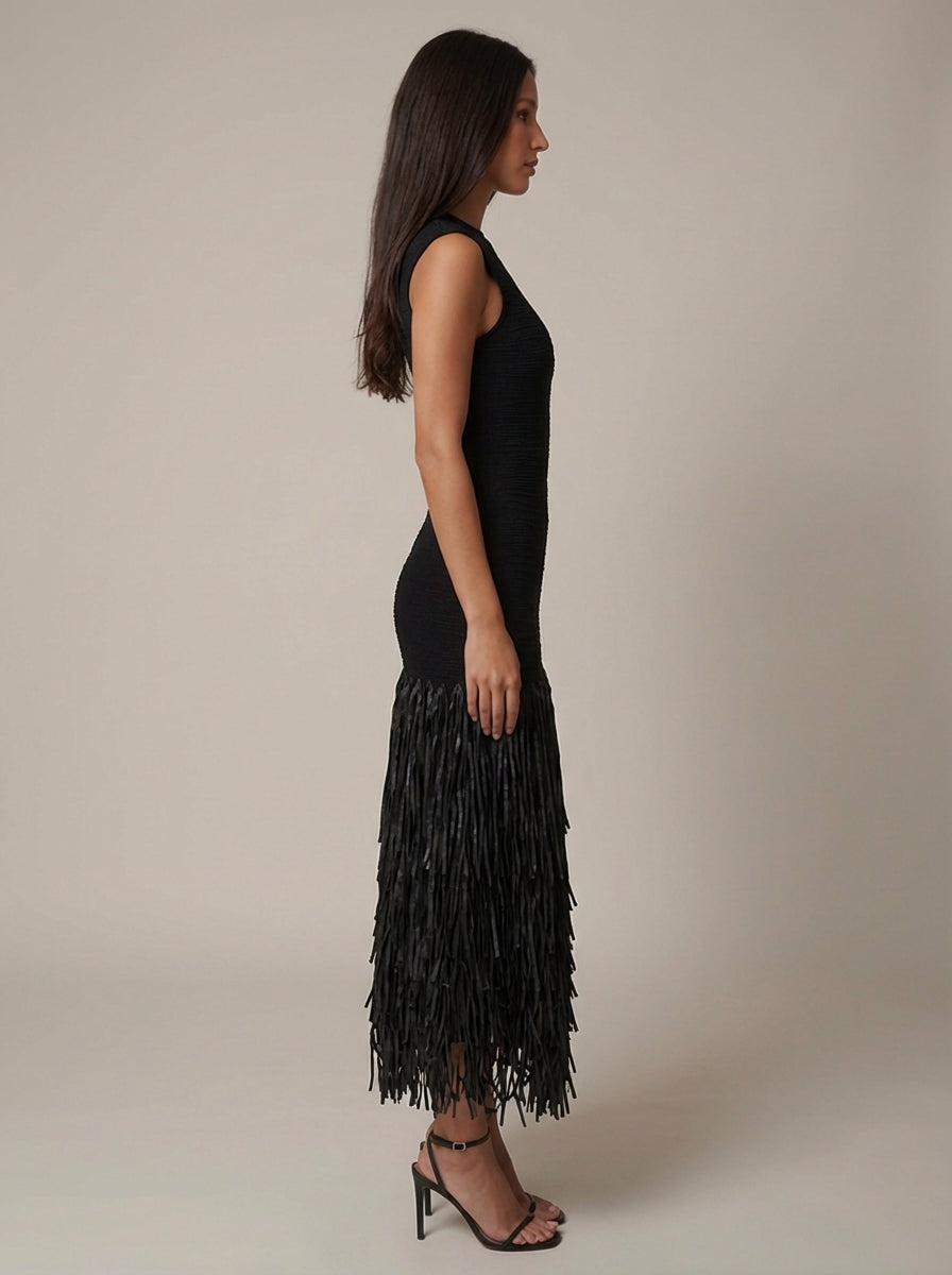 Side view close look at tiered black fringe skirt on sleeveless midi dress with ankle-strap heels